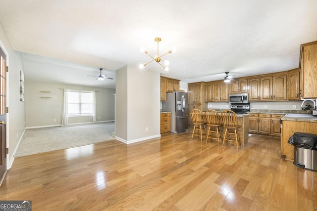 4407 Jones Rd, Macon, GA 31216 - kitchen with stainless steel appliances, ceiling fan, brown cabinets, open floor plan, and a chandelier