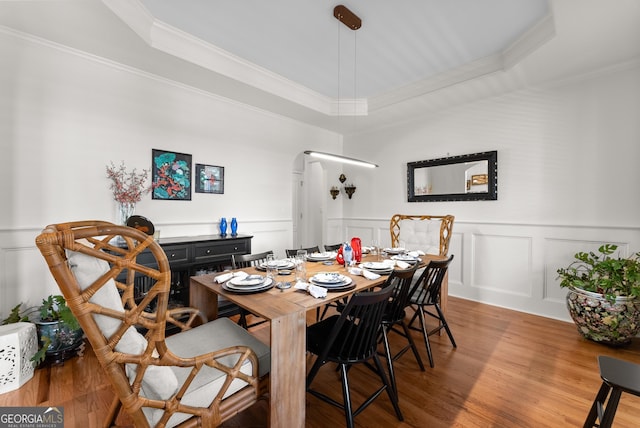 5176 Glen Forrest Dr, Flowery Branch, GA 30542 - dining room featuring ornamental molding, a raised ceiling, wood finished floors, a decorative wall, and arched walkways