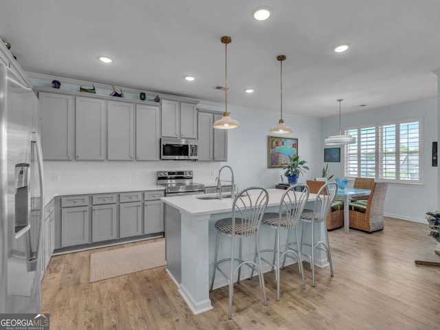 103 Crowley Dr, Calhoun, GA 30701 - kitchen featuring stainless steel appliances, gray cabinets, light wood-type flooring, a kitchen island with sink, and a breakfast bar area