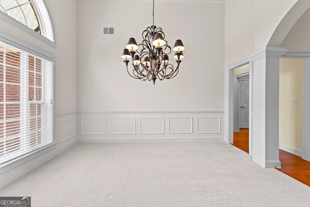 125 Lake Park Dr, Sharpsburg, GA 30277 - unfurnished dining area with a high ceiling, a chandelier, carpet flooring, and arched walkways