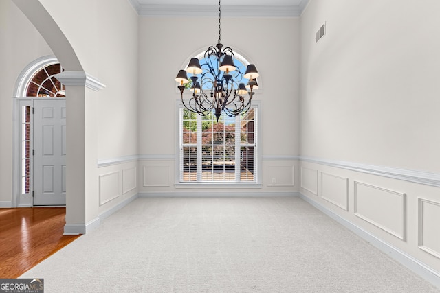 125 Lake Park Dr, Sharpsburg, GA 30277 - unfurnished dining area with a chandelier, arched walkways, carpet, ornamental molding, and a wainscoted wall