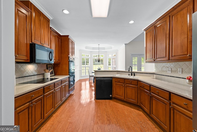 125 Lake Park Dr, Sharpsburg, GA 30277 - kitchen featuring black appliances, a sink, a peninsula, light wood-style flooring, and decorative backsplash