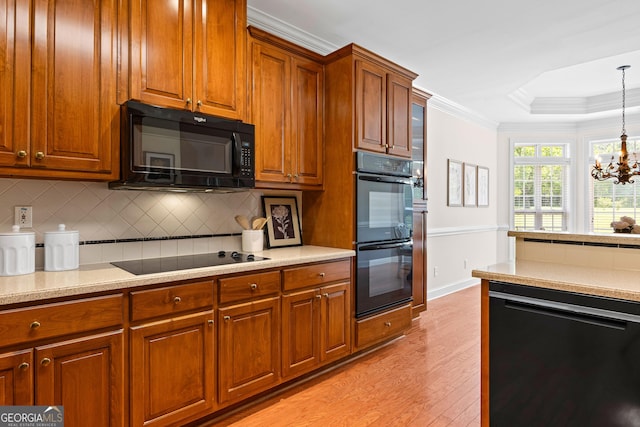 125 Lake Park Dr, Sharpsburg, GA 30277 - kitchen featuring black appliances, light wood-style flooring, tasteful backsplash, hanging light fixtures, and light countertops