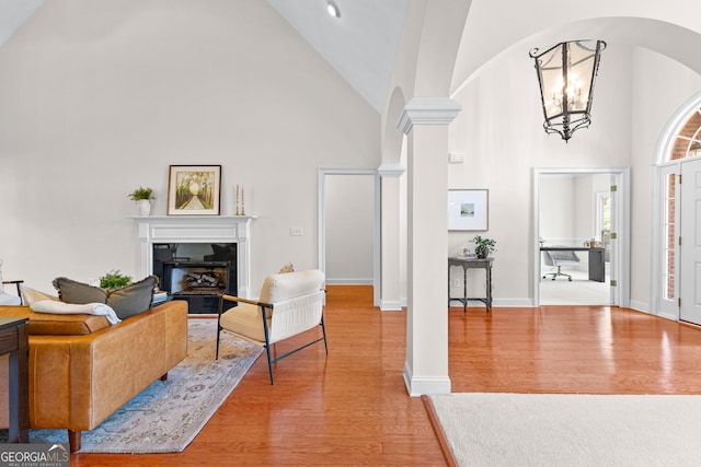 125 Lake Park Dr, Sharpsburg, GA 30277 - living room featuring high vaulted ceiling, decorative columns, arched walkways, light wood finished floors, and a fireplace