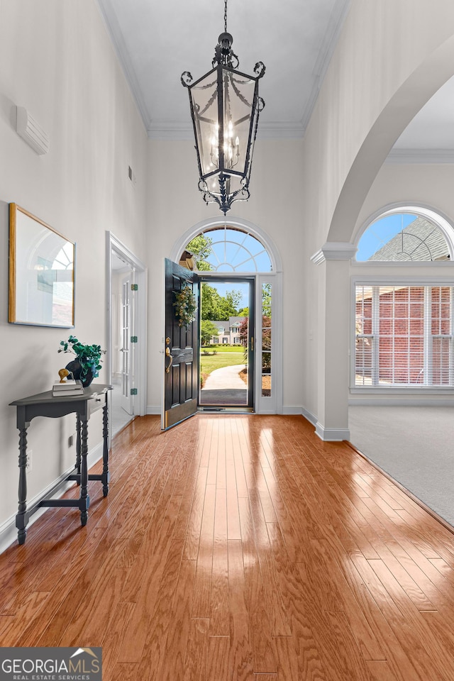 125 Lake Park Dr, Sharpsburg, GA 30277 - foyer entrance with arched walkways, a chandelier, a high ceiling, healthy amount of natural light, and wood-type flooring