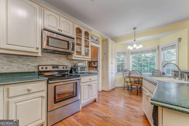 211 Westwood Dr, Calhoun, GA 30701 - kitchen featuring stainless steel appliances, dark countertops, a chandelier, light wood-style flooring, and tasteful backsplash