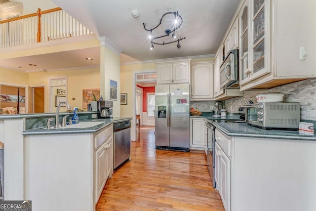 211 Westwood Dr, Calhoun, GA 30701 - kitchen featuring appliances with stainless steel finishes, a sink, light wood-style flooring, dark countertops, and glass insert cabinets