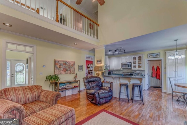 211 Westwood Dr, Calhoun, GA 30701 - living area featuring crown molding, light wood-style floors, a ceiling fan, a chandelier, and a high ceiling