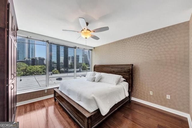 3338 Peachtree Rd NE Unit 508, Atlanta, GA 30326 - bedroom with baseboards, wallpapered walls, dark wood-style flooring, multiple windows, and ceiling fan