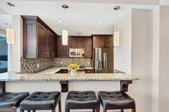 3338 Peachtree Rd NE Unit 508, Atlanta, GA 30326 - kitchen with appliances with stainless steel finishes, a peninsula, backsplash, light stone countertops, and pendant lighting