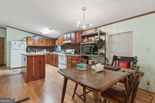 4369 River Rd, Folkston, GA 31537 - kitchen featuring white appliances, under cabinet range hood, brown cabinetry, a chandelier, and a kitchen island