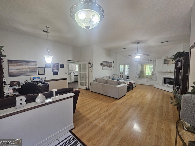 212 Hunting Ct, Jonesboro, GA 30236 - living area with a fireplace with raised hearth, light wood-style floors, a ceiling fan, lofted ceiling, and a textured ceiling