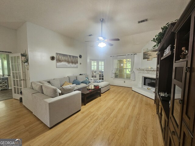 212 Hunting Ct, Jonesboro, GA 30236 - living area featuring french doors, light wood-style flooring, a ceiling fan, a brick fireplace, and a textured ceiling