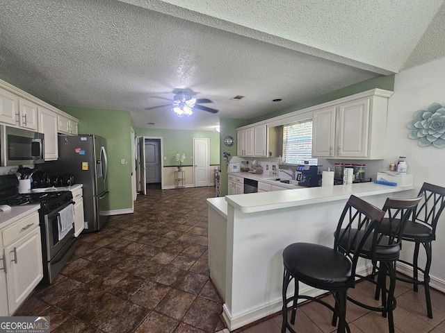 212 Hunting Ct, Jonesboro, GA 30236 - kitchen with stainless steel appliances, a peninsula, a breakfast bar area, light countertops, and baseboards