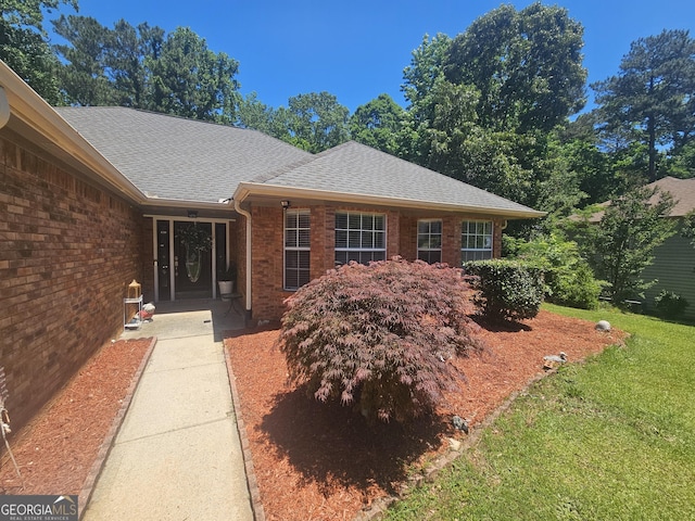 212 Hunting Ct, Jonesboro, GA 30236 - doorway to property featuring roof with shingles, brick siding, and a yard
