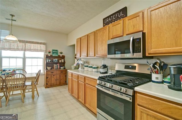 809 Longbranch Ln, Douglasville, GA 30134 - kitchen featuring appliances with stainless steel finishes, light countertops, light floors, decorative light fixtures, and a textured ceiling