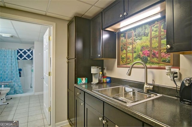 809 Longbranch Ln, Douglasville, GA 30134 - kitchen with a sink, a paneled ceiling, dark countertops, light tile patterned floors, and baseboards