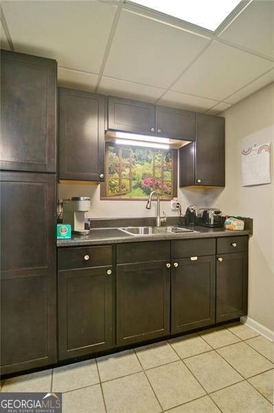809 Longbranch Ln, Douglasville, GA 30134 - kitchen featuring a sink, light tile patterned flooring, baseboards, a paneled ceiling, and dark countertops