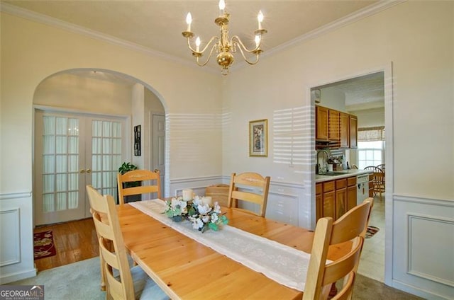 809 Longbranch Ln, Douglasville, GA 30134 - dining area featuring arched walkways, crown molding, a chandelier, french doors, and wood finished floors