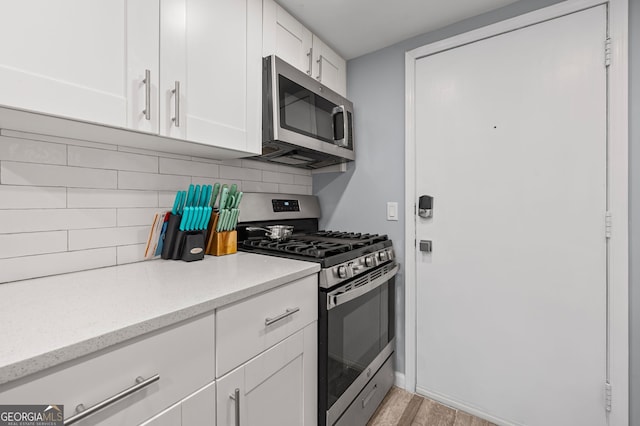 6851 Roswell Rd Unit E4, Sandy Springs, GA 30328 - kitchen with stainless steel appliances, tasteful backsplash, white cabinets, light stone countertops, and light wood-style floors