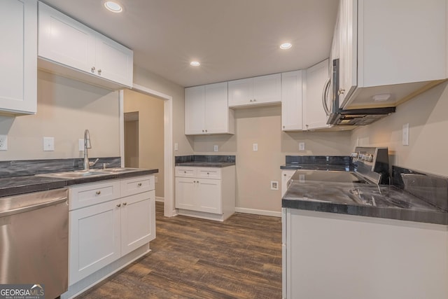 3107 Hendrix Cir SW, Covington, GA 30014 - kitchen featuring stainless steel appliances, dark countertops, a sink, dark wood finished floors, and white cabinetry