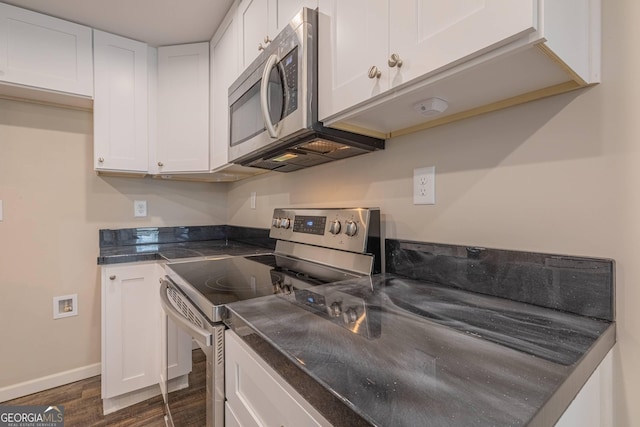 3107 Hendrix Cir SW, Covington, GA 30014 - kitchen with appliances with stainless steel finishes, dark countertops, dark wood finished floors, and white cabinetry