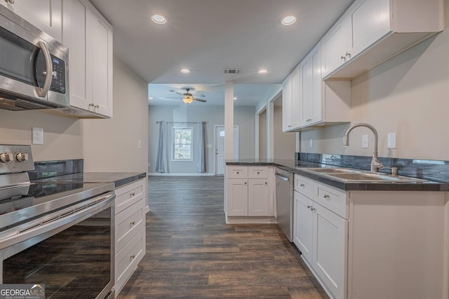 3107 Hendrix Cir SW, Covington, GA 30014 - kitchen featuring appliances with stainless steel finishes, a sink, dark wood-style flooring, ceiling fan, and dark countertops