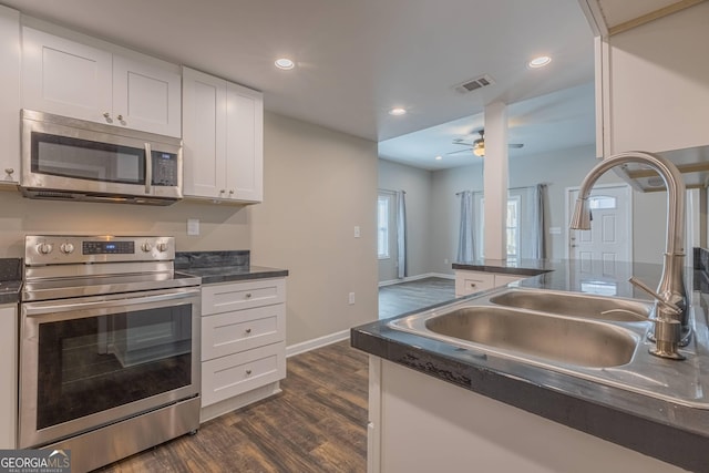 3107 Hendrix Cir SW, Covington, GA 30014 - kitchen with stainless steel appliances, a sink, dark countertops, dark wood-style flooring, and white cabinets