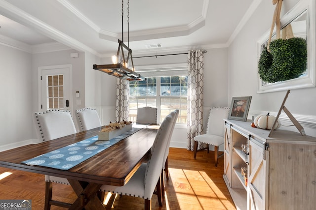 1412 Short Ct, Mcdonough, GA 30252 - dining room featuring light wood-type flooring, a raised ceiling, crown molding, a wainscoted wall, and baseboards