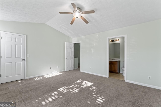11439 S Grove Dr, Hampton, GA 30228 - unfurnished bedroom with lofted ceiling, carpet flooring, baseboards, connected bathroom, and a textured ceiling