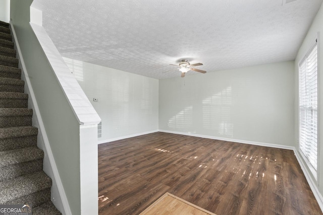 11439 S Grove Dr, Hampton, GA 30228 - unfurnished living room with a textured ceiling, dark wood-style flooring, ceiling fan, stairway, and baseboards