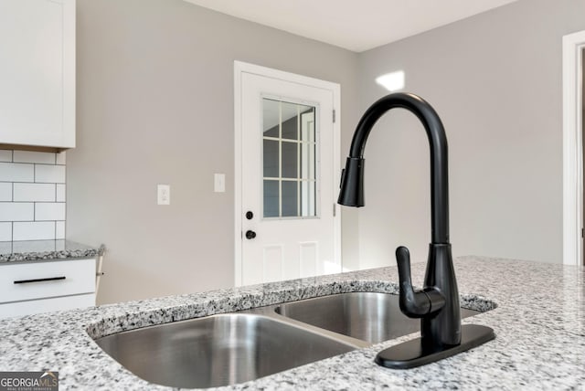 124 Stark St, Commerce, GA 30529 - kitchen view of backsplash, a sink, light stone counters, and white cabinets