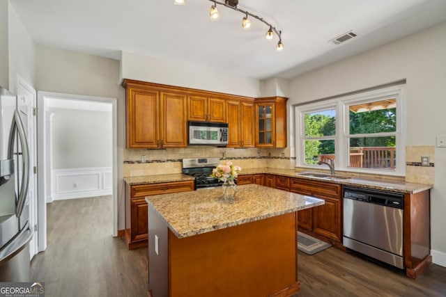 7025 Coffield Ct, Cumming, GA 30041 - kitchen with stainless steel appliances, a sink, brown cabinetry, light stone countertops, and tasteful backsplash