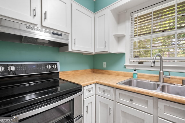 2933 King Alfred Dr, Macon, GA 31204 - kitchen featuring stainless steel range with electric stovetop, a sink, under cabinet range hood, light countertops, and white cabinetry