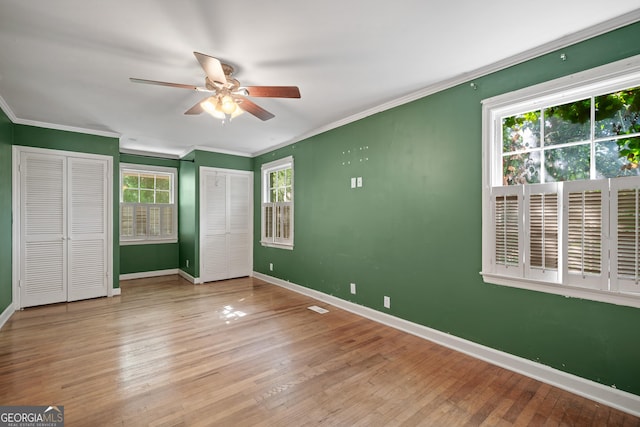 2933 King Alfred Dr, Macon, GA 31204 - unfurnished bedroom featuring baseboards, two closets, crown molding, wood-type flooring, and ceiling fan