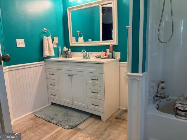 210 Vineyard Rd, Thomaston, GA 30286 - full bath featuring a wainscoted wall, vanity, wood finished floors, and bathtub / shower combination