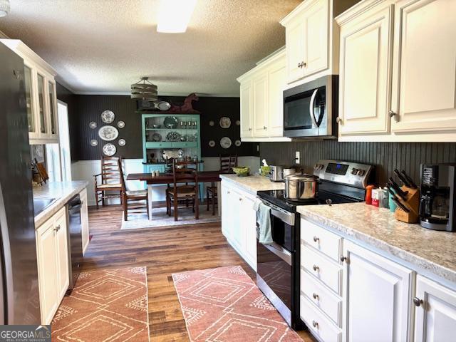 210 Vineyard Rd, Thomaston, GA 30286 - kitchen with stainless steel appliances, a textured ceiling, light countertops, wood finished floors, and glass insert cabinets