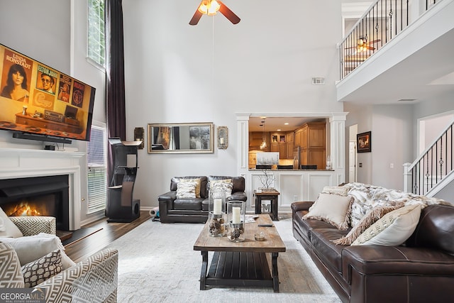 960 Pebblestone Ct, Alpharetta, GA 30009 - living room with a high ceiling, a ceiling fan, stairs, wood finished floors, and a lit fireplace