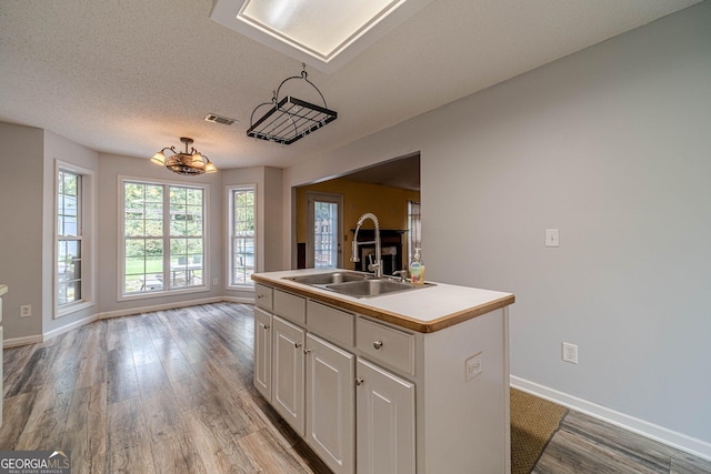 123 Chippewa Run, Auburn, GA 30011 - kitchen featuring a sink, a center island with sink, light wood-style floors, white cabinetry, and baseboards
