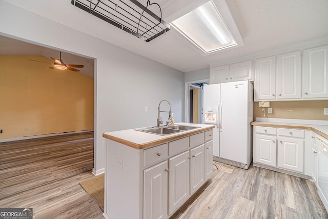 123 Chippewa Run, Auburn, GA 30011 - kitchen featuring a sink, white fridge with ice dispenser, light wood finished floors, white cabinets, and a kitchen island with sink