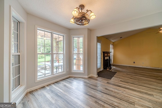 123 Chippewa Run, Auburn, GA 30011 - unfurnished living room with wood finished floors, a chandelier, a textured ceiling, baseboards, and a ceiling fan