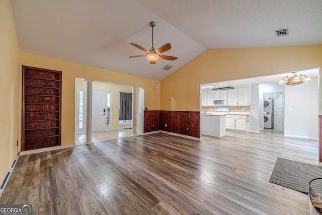 123 Chippewa Run, Auburn, GA 30011 - unfurnished living room with stacked washer / drying machine, light wood finished floors, a ceiling fan, ornate columns, and high vaulted ceiling
