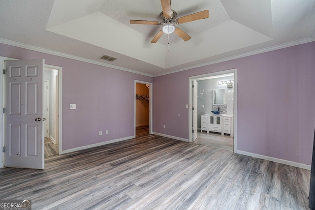 123 Chippewa Run, Auburn, GA 30011 - unfurnished bedroom featuring a raised ceiling, wood finished floors, ensuite bath, a walk in closet, and crown molding