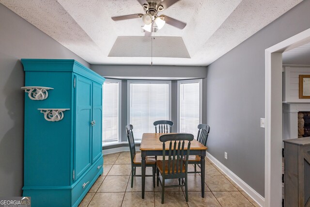 102 Fern Way, Thomaston, GA 30286 - dining room with a tray ceiling, light tile patterned floors, a textured ceiling, ceiling fan, and a stone fireplace
