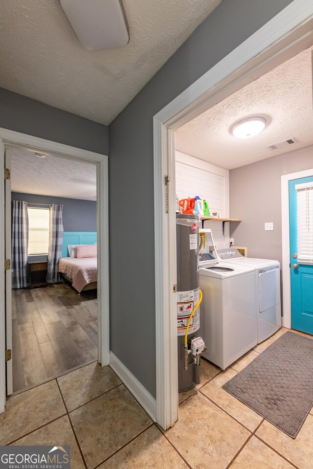 102 Fern Way, Thomaston, GA 30286 - laundry area featuring water heater, a textured ceiling, washing machine and clothes dryer, light tile patterned flooring, and plenty of natural light