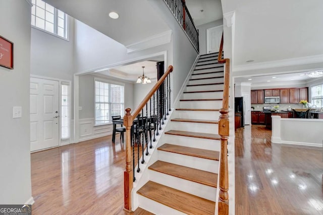 475 Bayswater Way, Suwanee, GA 30024 - entryway featuring a chandelier, stairway, crown molding, light wood-style flooring, and a wainscoted wall