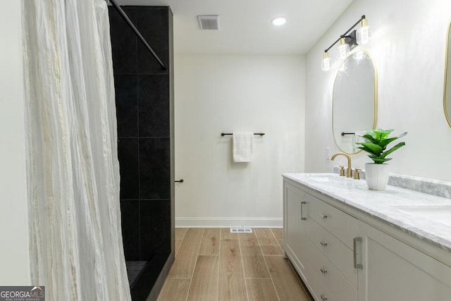 398 Baker Cir NW, Atlanta, GA 30318 - bathroom featuring double vanity, baseboards, a tile shower, wood finish floors, and recessed lighting