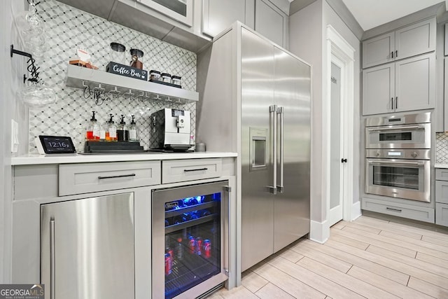 2804 Skyland Dr NE, Brookhaven, GA 30341 - indoor dry bar with wine cooler, backsplash, light wood-style floors, and appliances with stainless steel finishes