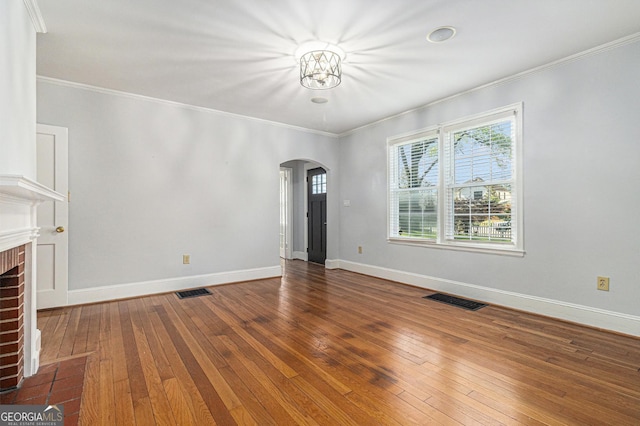 2701 Log Cabin Dr SE, Atlanta, GA 30339 - unfurnished living room with arched walkways, a fireplace, crown molding, hardwood / wood-style flooring, and baseboards
