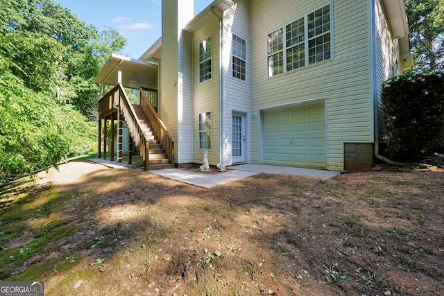 1315 Crane Ct, Mcdonough, GA 30252 - rear view of house featuring stairway, a garage, a chimney, and a wooden deck